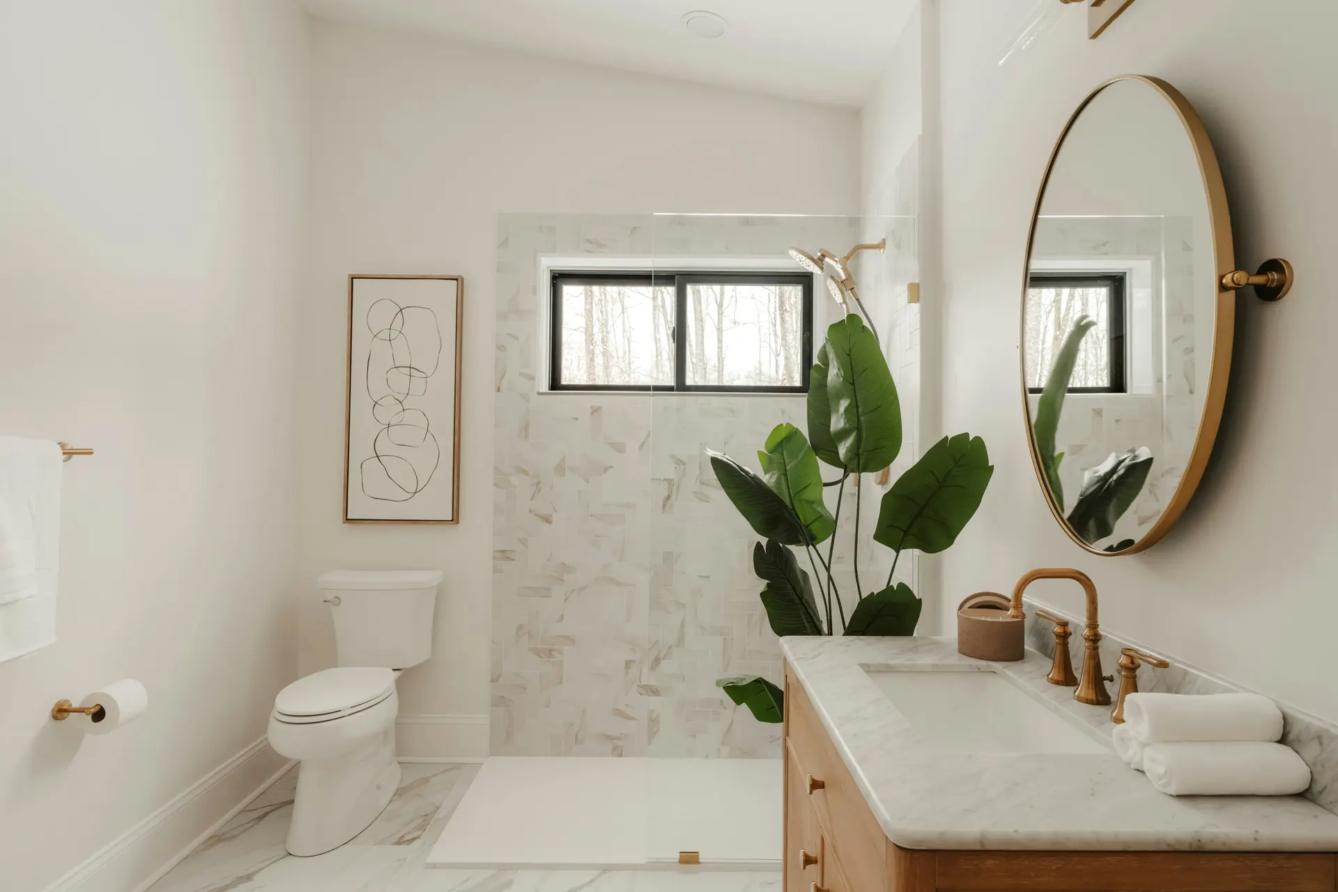 Bathroom with a marble-tiled shower, wood vanity and round mirror