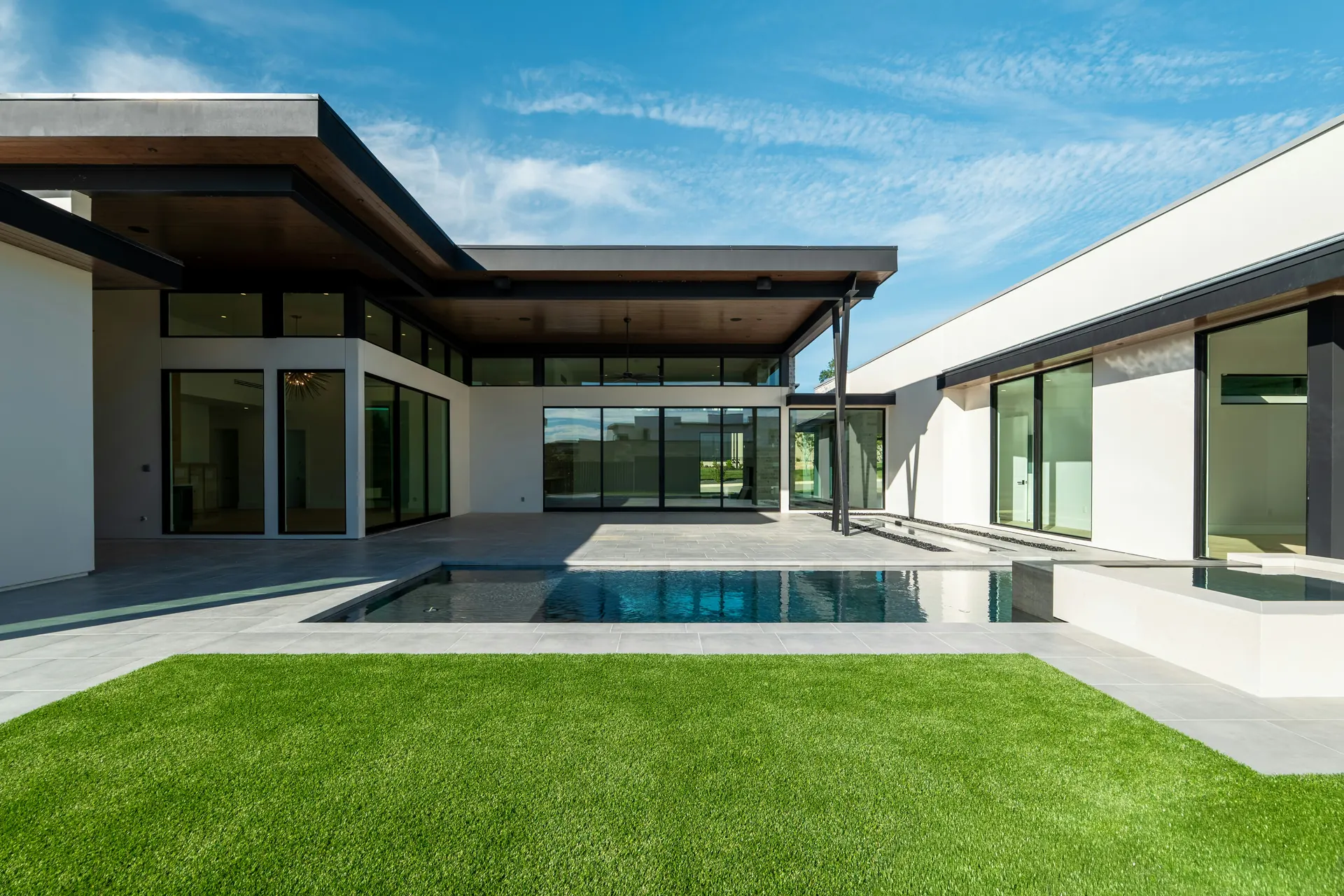 Single-story modern house with a covered patio, pool and lawn